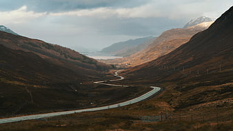 Winding road through Scottish Highlands valley landscape