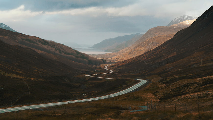 Winding road through Scottish Highlands valley landscape
