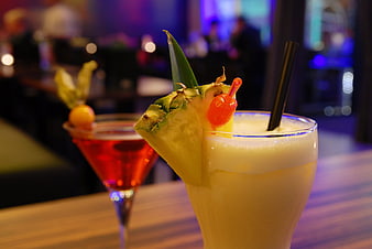 Tropical pineapple cocktail with creamy foam and red cherry garnish in a bar