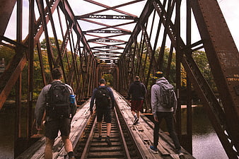 Group of Hikers Walking on Rusty Railroad Bridge