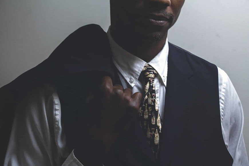 Man in Vest and Patterned Tie Adjusting Jacket