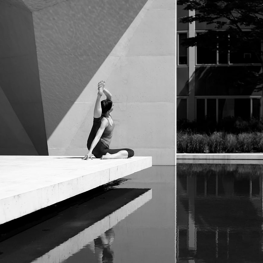 Woman doing yoga pose by pool in black and white