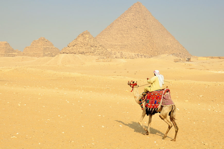 Egyptian Rider On Camel In Desert Before Pyramids
