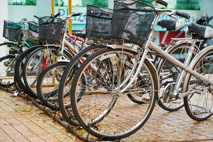 Row of parked bicycles with baskets on city sidewalk