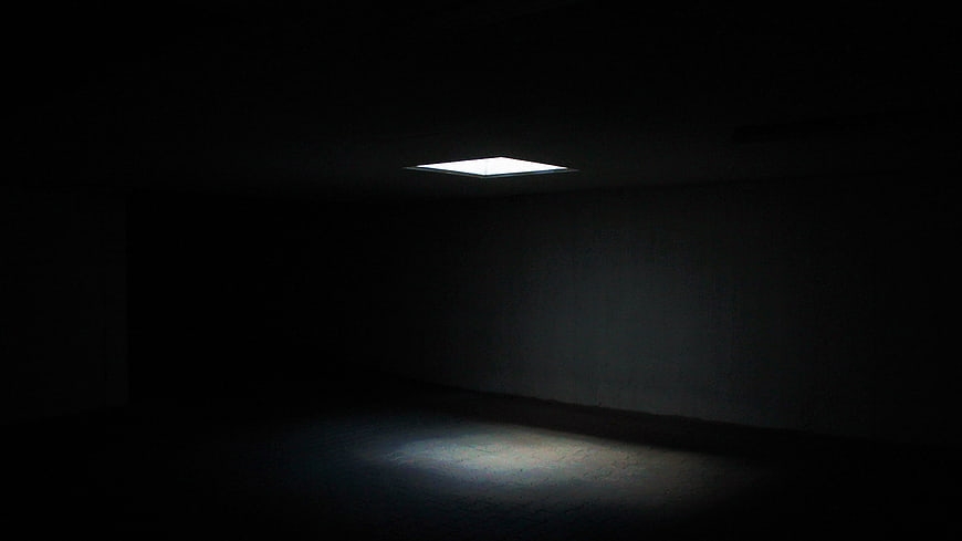 Single skylight illuminating dark empty room interior