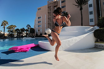Woman in Bikini Kicking Soccer Ball by Poolside