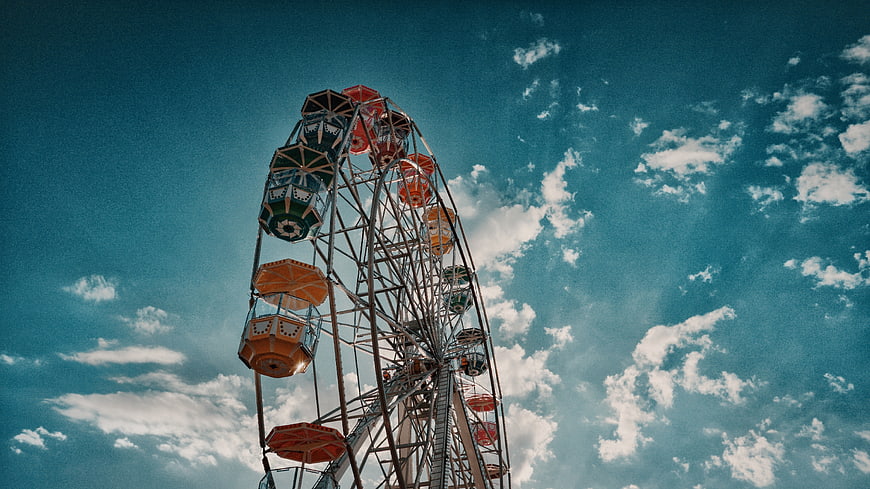 Vintage Ferris Wheel Against Blue Sky with Clouds