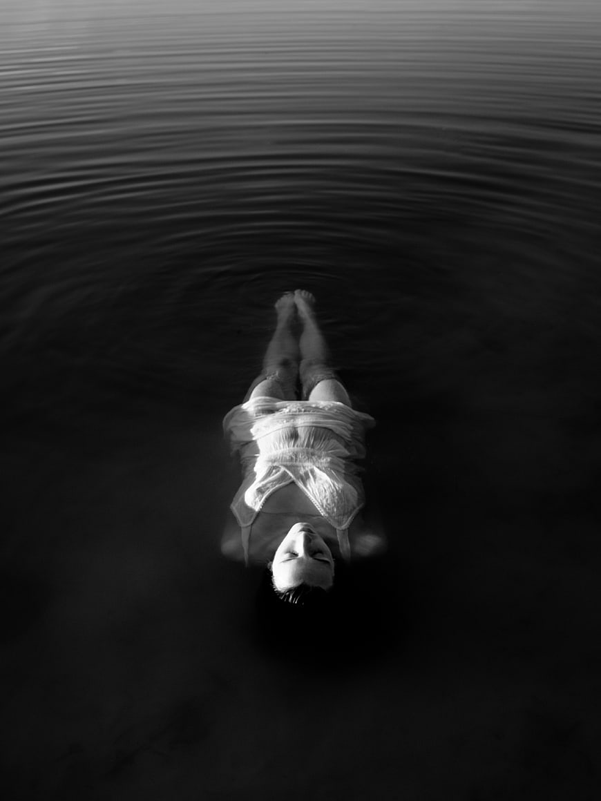 Woman floating in dark water black and white photo