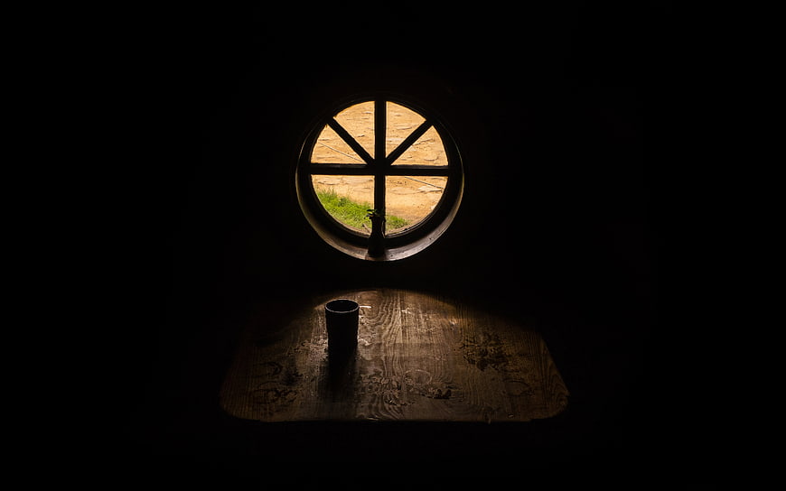Dark moody interior with round window and wooden table