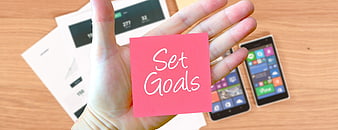 Hand holding pink sticky note with Set Goals text