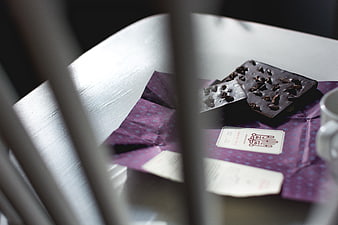 Dark chocolate pieces on purple wrapper with coffee cup