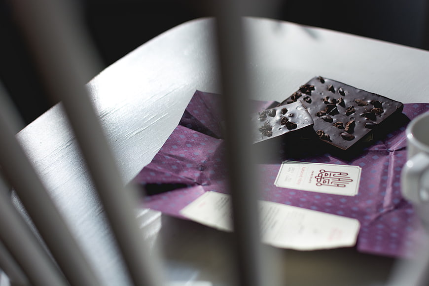 Dark chocolate pieces on purple wrapper with coffee cup
