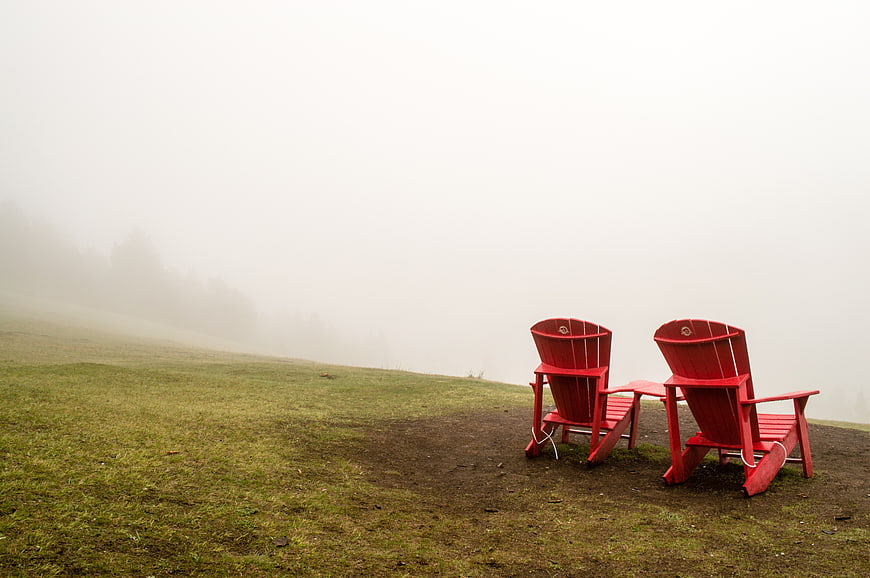 Two Red Adirondack Chairs in Foggy Meadow