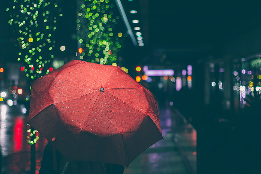 Red Umbrella in Rainy City Night with Bokeh Lights