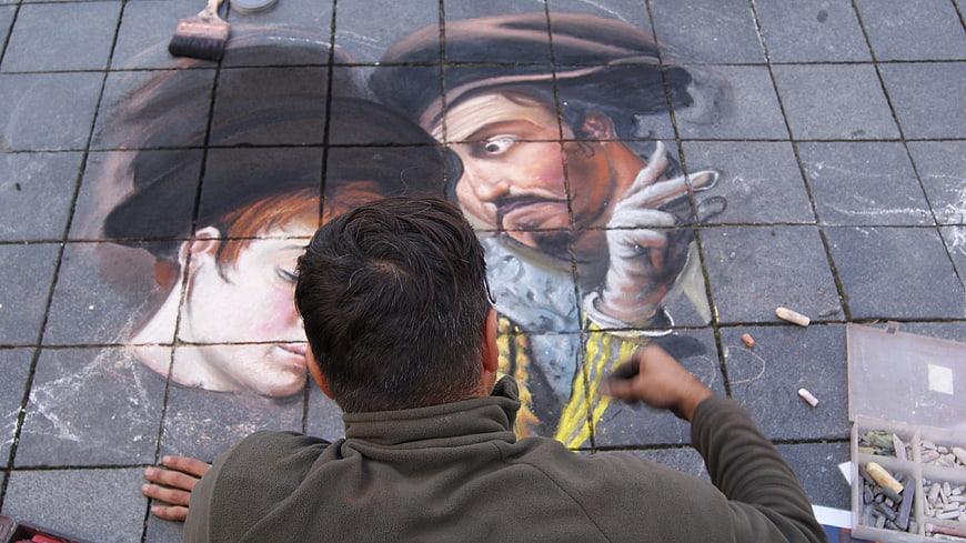 Street artist creating 3D chalk pavement art