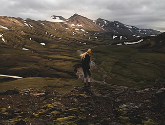 Woman hiking in mossy Icelandic highlands with mountains