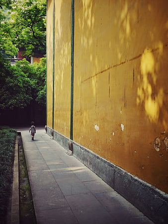Child walking along yellow temple wall in China