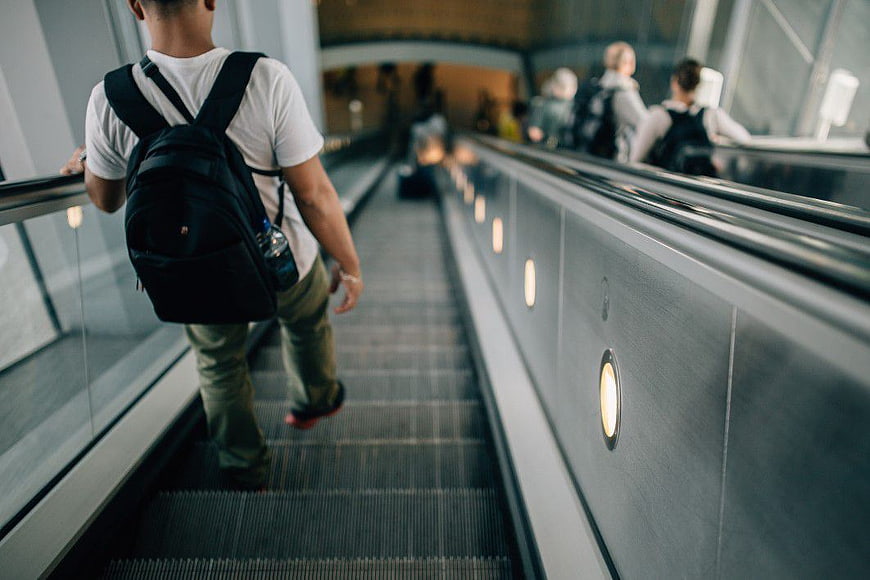 Man with Backpack Riding Down Escalator