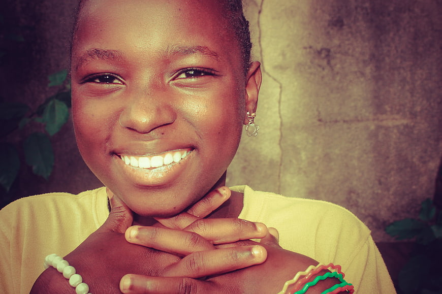 Close-up portrait of smiling African girl with hands on chin