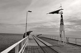 Black and white pier with weather vane and sea view