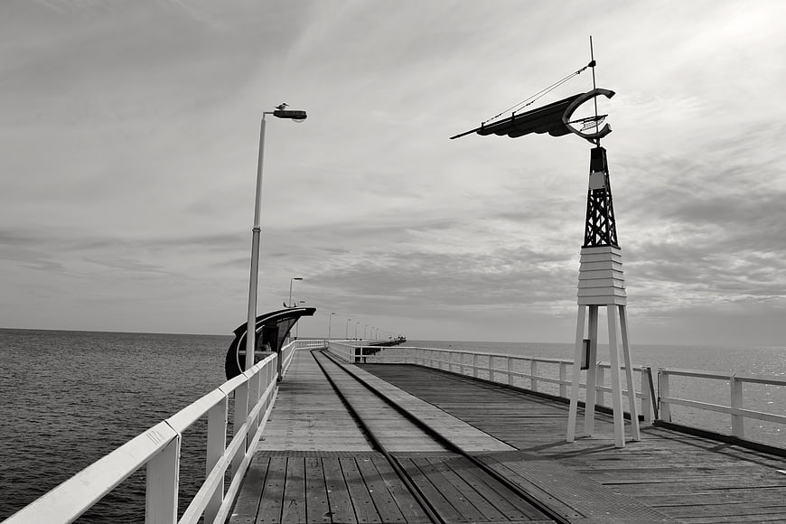 Black and white pier with weather vane and sea view