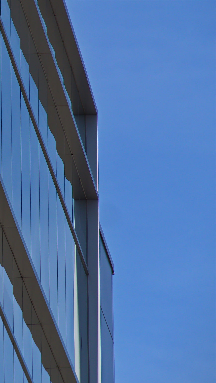 Modern Glass Office Building Facade Against Blue Sky