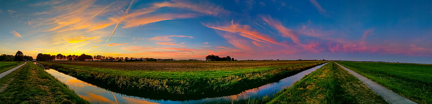 Panoramic sunset over Dutch polder landscape with canal