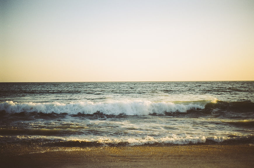Serene Ocean Waves Rolling onto Sandy Beach at Sunset