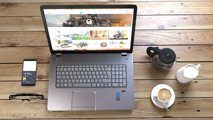 Top view of laptop workspace with coffee and smartphone on wooden desk