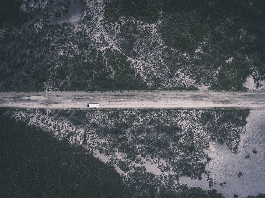 Aerial view of white van on snowy forest road