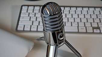Vintage Chrome Microphone on Desk with Blurred Keyboard Background
