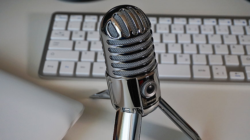 Vintage Chrome Microphone on Desk with Blurred Keyboard Background