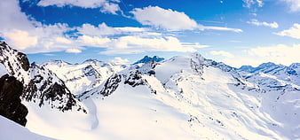 Panoramic View of Snow-Covered Mountain Peaks Under Blue Sky