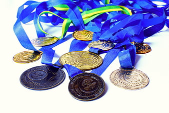 Collection of gold, silver, and bronze medals with blue ribbons on white background