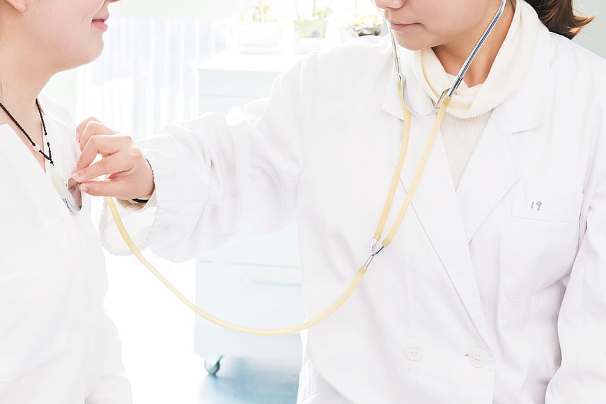 Doctor Using Stethoscope on Patient in Clinic