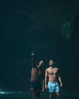 Two Men Pointing Up in Dark Tropical Water