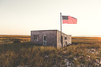 Rustic Beach Cottage with American Flag at Sunset