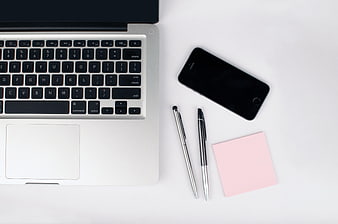 Minimalist workspace with laptop, smartphone, and pink sticky note