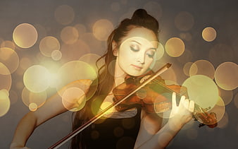 Woman playing violin with golden bokeh lights