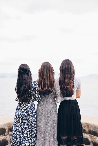 Three women looking at the ocean from behind