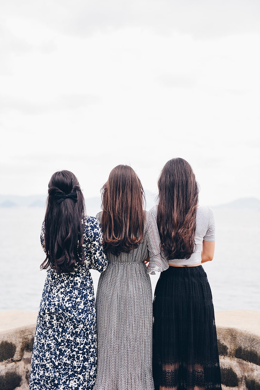 Three women looking at the ocean from behind