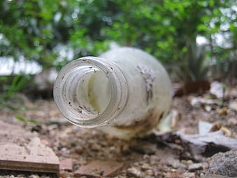 Dirty glass bottle lying on ground in nature