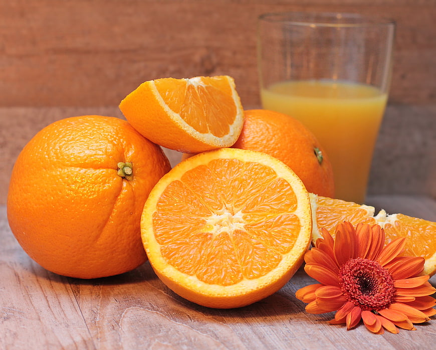 Fresh Oranges, Orange Juice, and Gerbera Daisy on Rustic Wooden Table