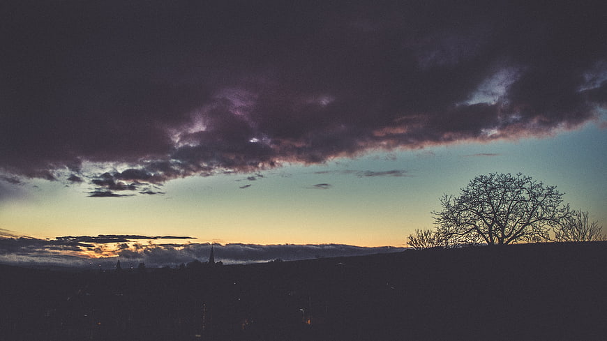 Dramatic purple and teal sunset sky over silhouetted landscape