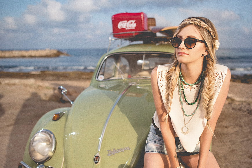 Blonde Woman with Braids Leaning on Vintage Green Beetle at Beach