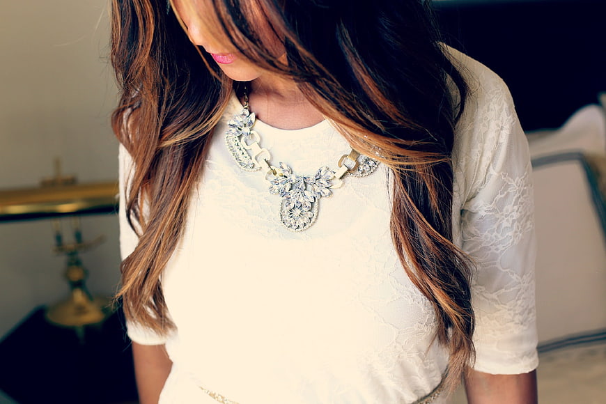 Woman Wearing Statement Necklace and White Lace Top