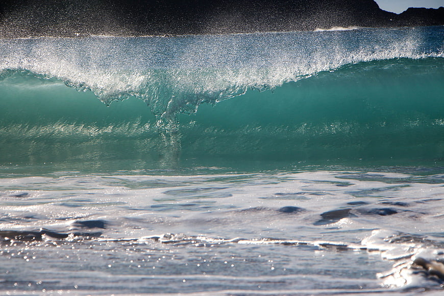 Powerful turquoise ocean wave crashing with white foam