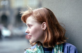 Candid profile of a red-haired woman leaning against a wall