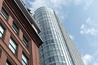 Low angle view of modern glass skyscraper and historic brick building