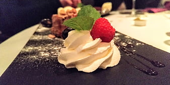 Close-up of whipped cream dessert with raspberry and mint